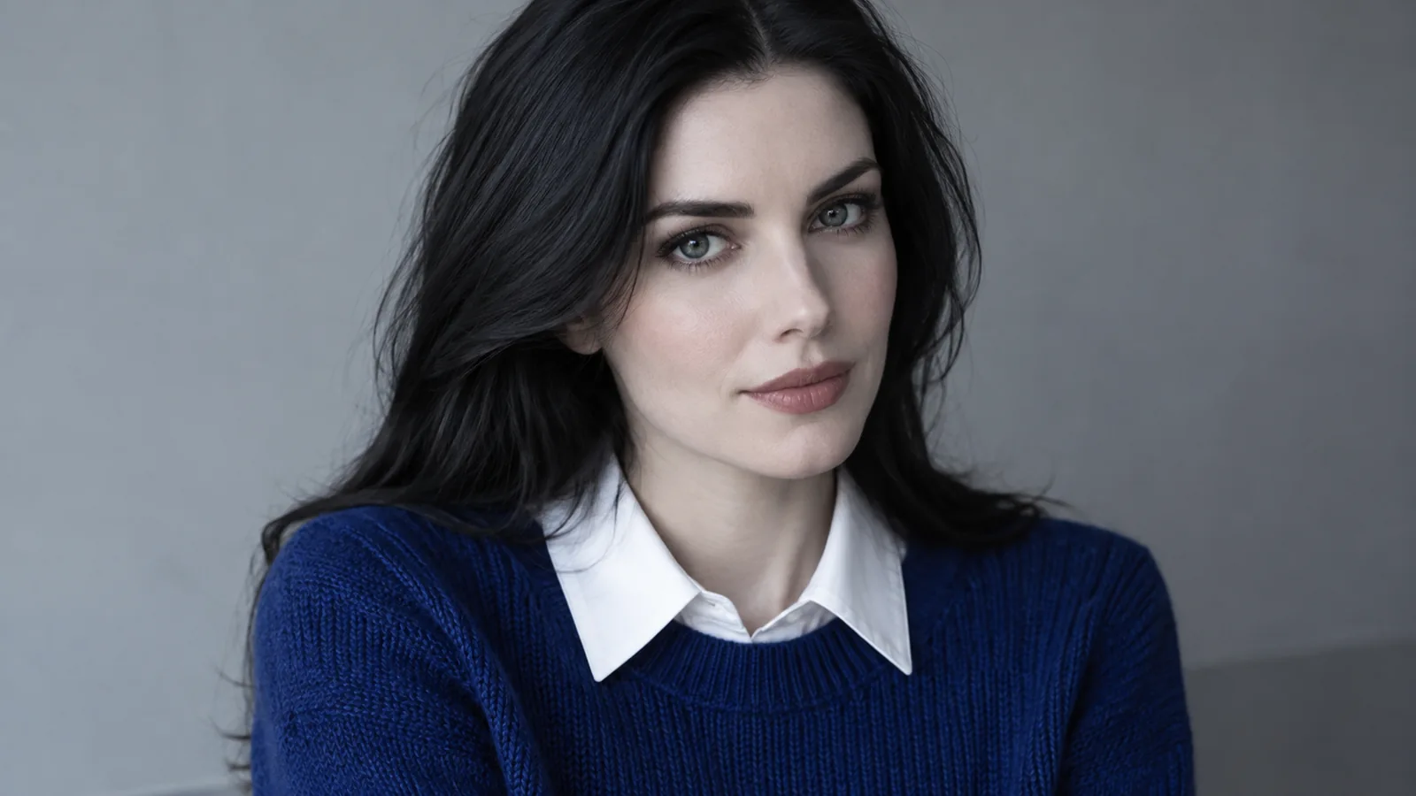 Fair Deep Winter woman in a deep sapphire sweater with an icy white collar against a grey wall
